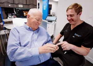 Dr. Bill Keith showing elderly patient tooth model at Keith & Associates Dental Implant Center in North Dinwiddie, VA.